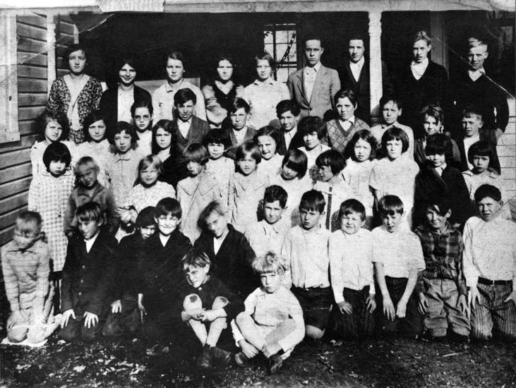 Black and white class photograph from the Dranesville School. 48 students are pictured. They are posed in front of the schoolhouse.