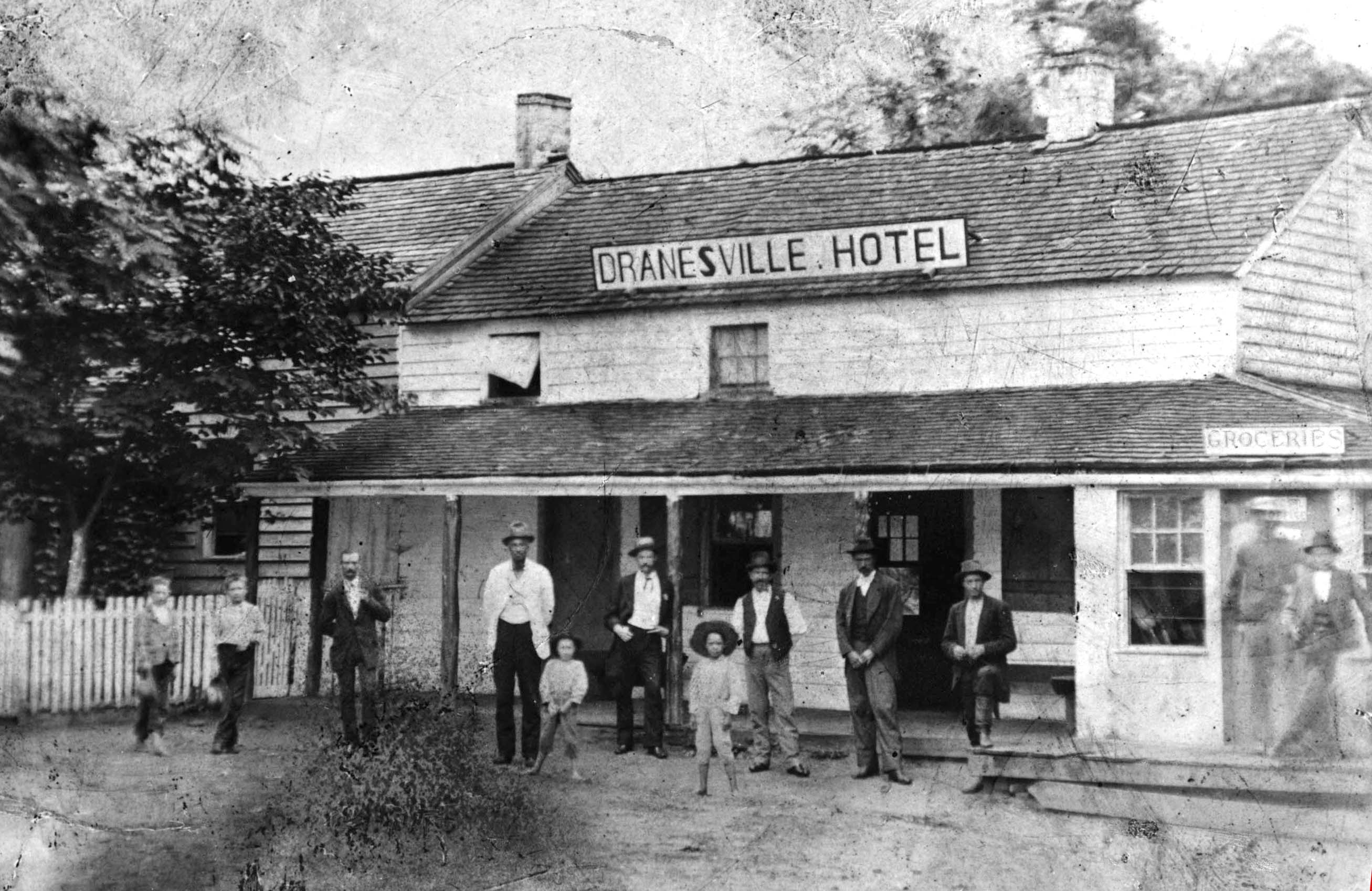 19th century photograph of the Dranesville Hotel. Adults and children stand in front of the building.