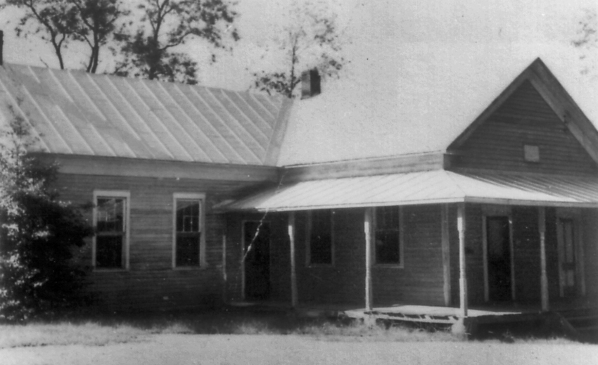 Black and white photograph of the two-room Dranesville School. One of the rooms has a roofed wrap-around porch.