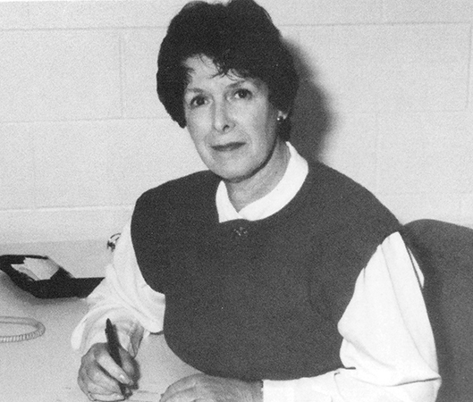 Black and white photograph of Principal Joan Freck sitting at her desk from the 1993 to 1994 yearbook.