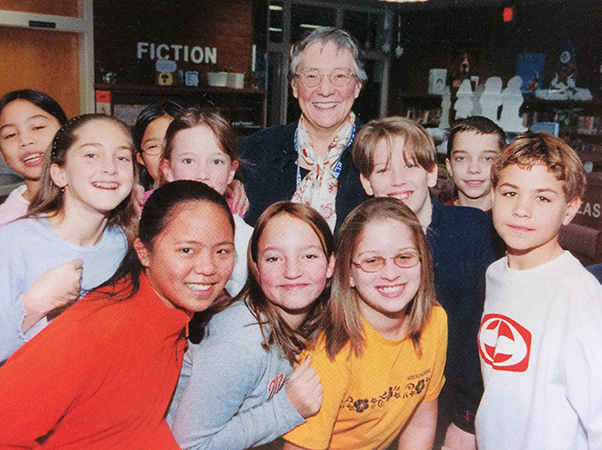 Color photograph of Principal Morrison from the 2001 to 2002 yearbook. She is standing behind a group of ten students. Everyone is smiling broadly.