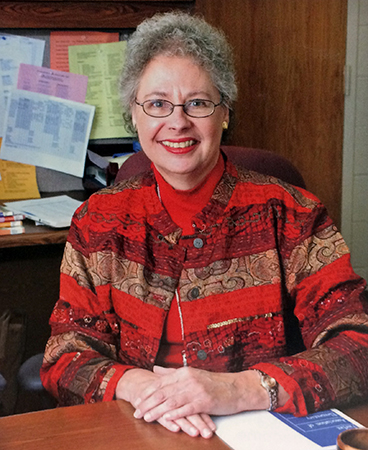 Color photograph of Principal Romberg seated at her desk from the 2003 to 2004 yearbook.